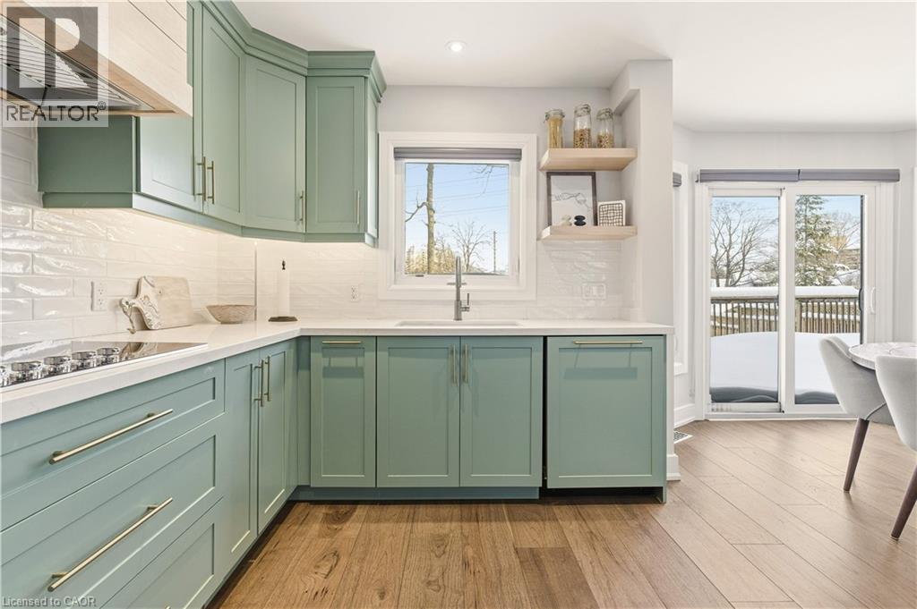 Kitchen featuring green cabinets, wall chimney range hood, light wood-type flooring, decorative backsplash, and recessed lighting - 697 Lambshead Drive, Burlington, ON - Indoor Photo Showing Kitchen