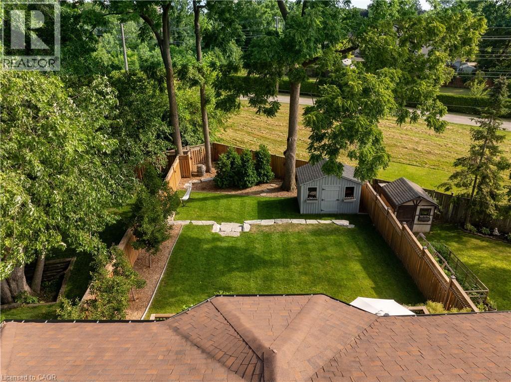 Fenced backyard with an outbuilding, a patio area, and view of scattered trees - 697 Lambshead Drive, Burlington, ON - Outdoor