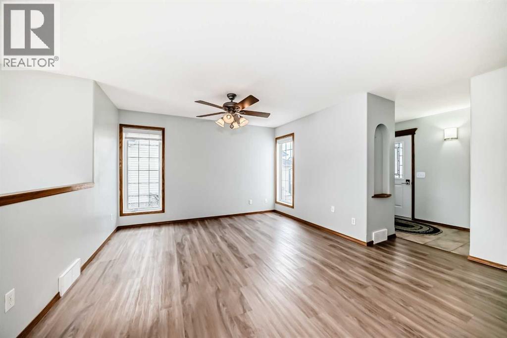 Bright living room with big windows and ceiling fan - 21 Hillview Road, Strathmore, AB - Indoor Photo Showing Other Room