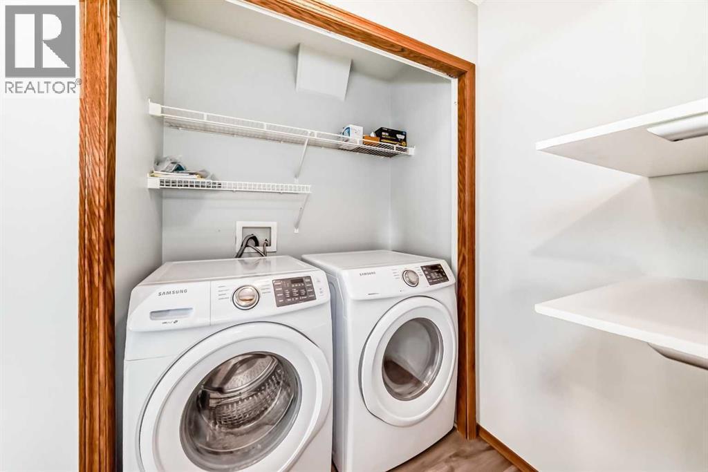 Main level laundry area with shelving. Washer and dryer are 2 years old - 21 Hillview Road, Strathmore, AB - Indoor Photo Showing Laundry Room