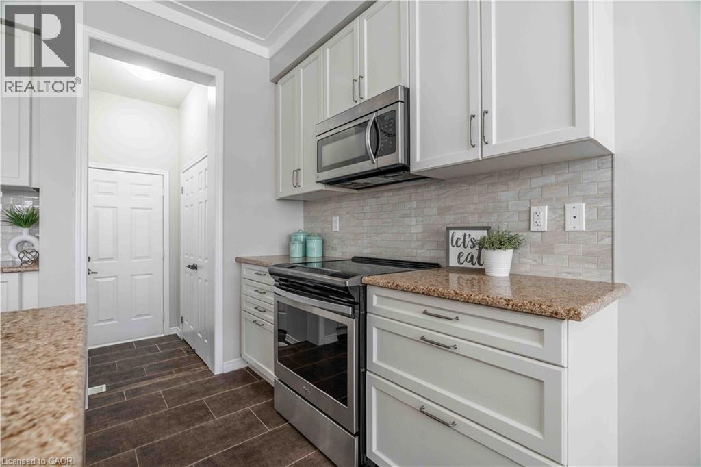 Kitchen with appliances with stainless steel finishes, decorative backsplash, and light stone counters - 115 Larry Crescent, Caledonia, ON - Indoor Photo Showing Kitchen