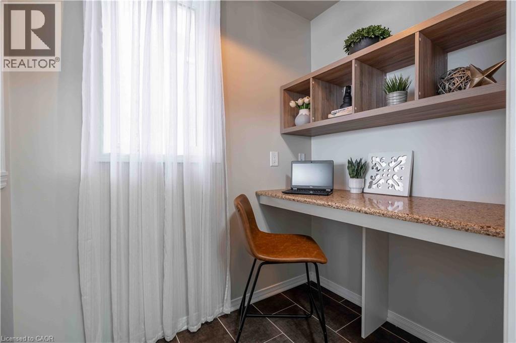Office area featuring built in desk and dark tile patterned flooring. A large window invites the outside in. - 115 Larry Crescent, Caledonia, ON - Indoor Photo Showing Office