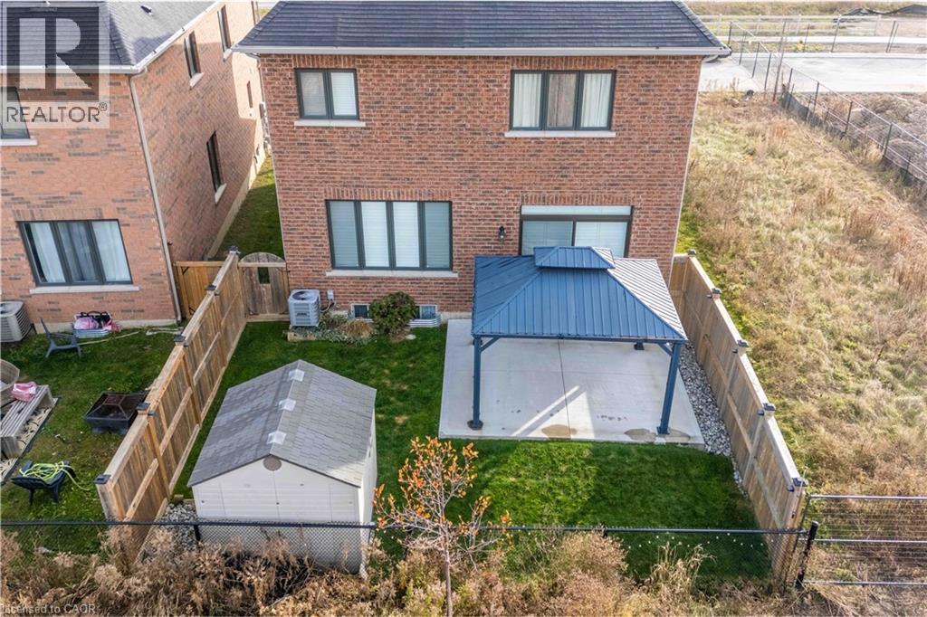 Back of property featuring a fenced and gated backyard, brick siding, gazebo, showing greenspace beyond. - 115 Larry Crescent, Caledonia, ON - Outdoor With Exterior