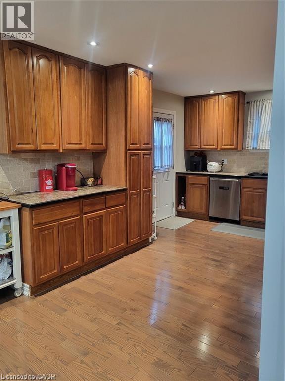 Kitchen featuring tasteful backsplash, light wood finished floors, stainless steel dishwasher, brown cabinetry, and light countertops - 18 Rosewell Street, Hamilton, ON - Indoor Photo Showing Kitchen