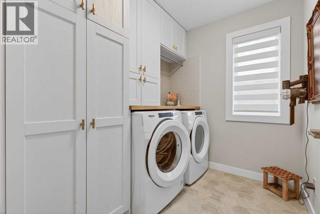 Updated second level laundry room with built-in cabinetry, countertop and rail - 307 Precedence Hill, Cochrane, AB - Indoor Photo Showing Laundry Room