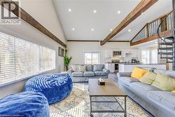 Living room featuring high vaulted ceiling, healthy amount of natural light, beam ceiling, recessed lighting, and wood finished floors -