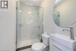 Bathroom featuring a marble finish shower, toilet, and vanity -