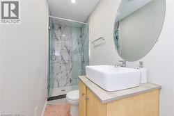 Bathroom with a marble finish shower, toilet, vanity, baseboards, and recessed lighting -