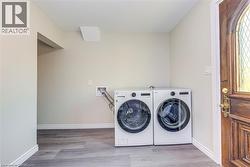 Laundry area with washing machine and dryer, wood finished floors, and baseboards -