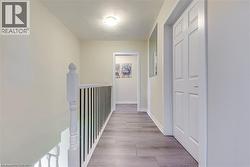 Hallway featuring an upstairs landing, wood finished floors, and baseboards -