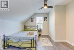Bedroom with wood finished floors, lofted ceiling, a ceiling fan, and baseboards -