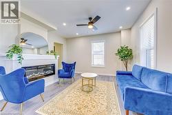 Living room with a ceiling fan, a glass covered fireplace, wood finished floors, baseboards, and recessed lighting -