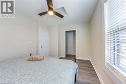 Bedroom with dark wood-style floors, ceiling fan, and baseboards -