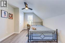 Bedroom with wood finished floors, lofted ceiling, baseboards, and ceiling fan -