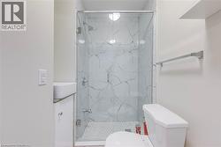 Full bath featuring toilet and a marble finish shower -