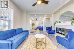 Living room featuring ceiling fan, a glass covered fireplace, wood finished floors, baseboards, and recessed lighting -