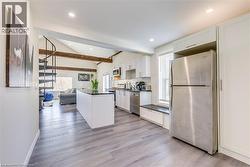 Kitchen featuring appliances with stainless steel finishes, dark countertops, white cabinetry, light wood-style floors, and recessed lighting -