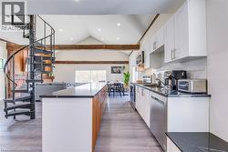 Kitchen with stainless steel appliances, dark countertops, white cabinets, vaulted ceiling, and recessed lighting -