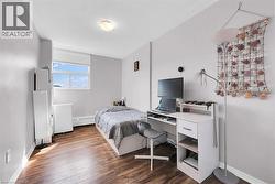 Bedroom with radiator, wood finished floors, and baseboards -