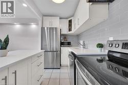Kitchen with light tile patterned floors, white cabinets, light countertops, appliances with stainless steel finishes, and decorative backsplash -