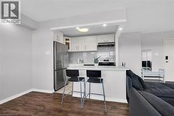 Kitchen featuring white cabinets, open floor plan, light countertops, under cabinet range hood, and stainless steel appliances -