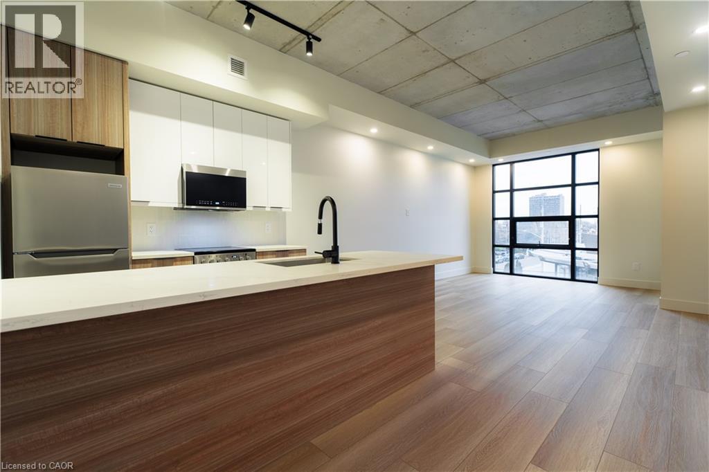 Kitchen featuring appliances with stainless steel finishes, modern cabinets, light wood-type flooring, white cabinetry, and open floor plan - 24 Augusta Street Unit# 305, Hamilton, ON - Indoor