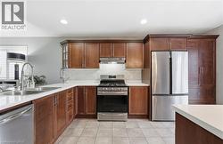 Kitchen with appliances with stainless steel finishes, under cabinet range hood, decorative backsplash, light tile patterned flooring, and recessed lighting -