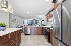 Kitchen featuring appliances with stainless steel finishes, lofted ceiling, decorative light fixtures, a chandelier, and under cabinet range hood -
