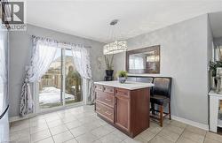 Kitchen featuring light countertops, hanging light fixtures, light tile patterned floors, freestanding refrigerator, and dark brown cabinetry -