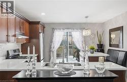 Kitchen featuring appliances with stainless steel finishes, pendant lighting, under cabinet range hood, a peninsula, and tasteful backsplash -