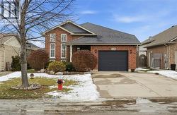 View of front of home featuring driveway, an attached garage, brick siding, and a shingled roof -