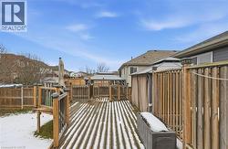 Snow covered deck with a fenced backyard and a residential view -