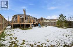 Snow covered house with a fenced backyard, a deck, and an outdoor fire pit -