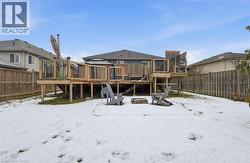 Snow covered rear of property featuring a fenced backyard and a deck -