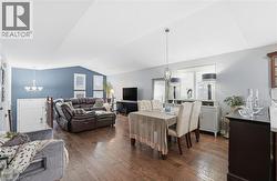 Dining area featuring a chandelier, vaulted ceiling, dark wood finished floors, and plenty of natural light -