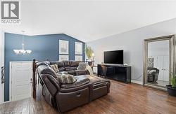 Living area featuring hardwood / wood-style floors, a chandelier, and vaulted ceiling -