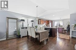 Dining room featuring plenty of natural light, a chandelier, dark wood-style floors, and vaulted ceiling -