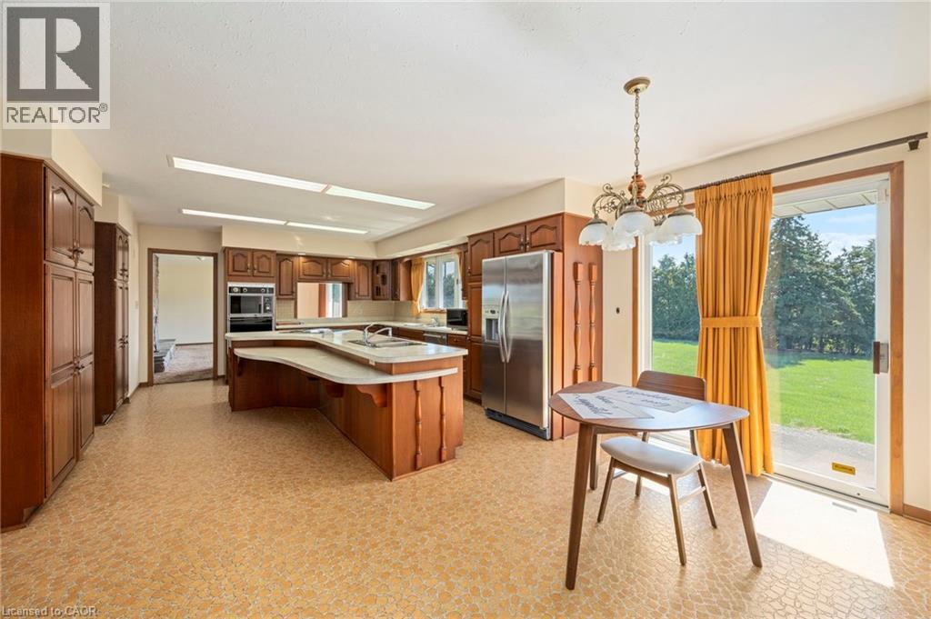 Kitchen with light flooring, stainless steel appliances, an island with sink, and a kitchen breakfast bar - 6828 Third Line, Chatham, ON