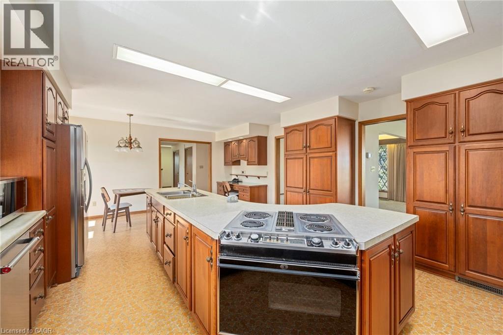 Kitchen with stainless steel appliances, brown cabinets, light countertops, and a kitchen island with sink - 6828 Third Line, Chatham, ON