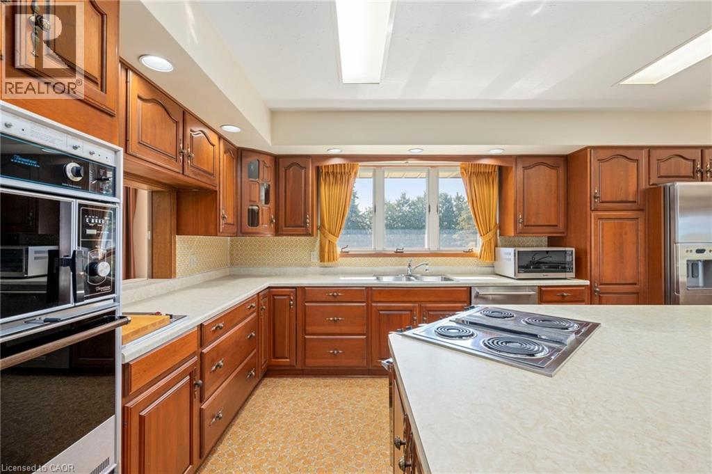Kitchen featuring brown cabinets, stainless steel appliances, light countertops, light flooring, and tasteful backsplash - 6828 Third Line, Chatham, ON