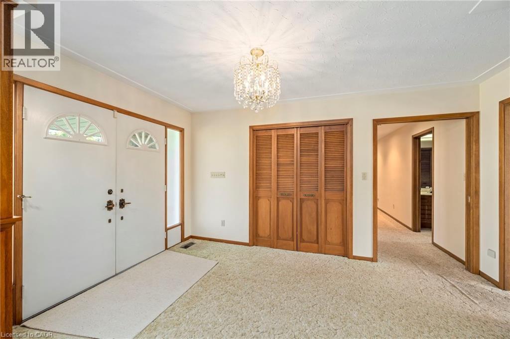 Carpeted entrance foyer with a chandelier and baseboards - 6828 Third Line, Chatham, ON