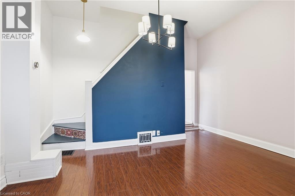 Unfurnished living room with dark wood-style flooring and a chandelier - 313 Mary Street, Hamilton, ON - Indoor Photo Showing Other Room