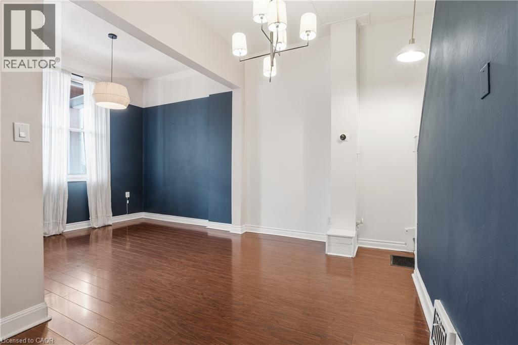Unfurnished dining area with dark wood-type flooring and a chandelier - 313 Mary Street, Hamilton, ON - Indoor Photo Showing Other Room