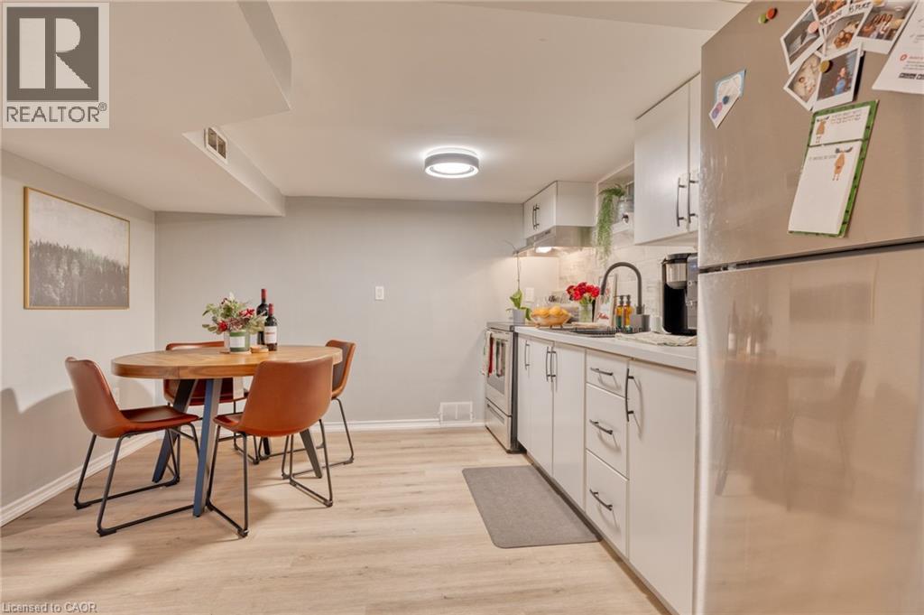 Kitchen featuring white cabinetry, sink, stainless steel appliances, backsplash, and light hardwood / wood-style floors - 99 East 36Th Street, Hamilton, ON - Indoor