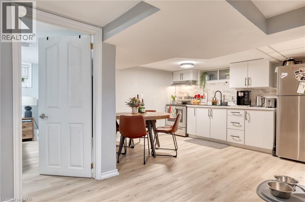 Kitchen featuring backsplash, white cabinets, sink, appliances with stainless steel finishes, and light hardwood / wood-style floors - 99 East 36Th Street, Hamilton, ON - Indoor Photo Showing Kitchen