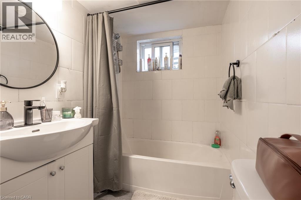 Bathroom with vanity, tile walls, shower / bath combo with shower curtain, and backsplash - 99 East 36Th Street, Hamilton, ON - Indoor Photo Showing Bathroom