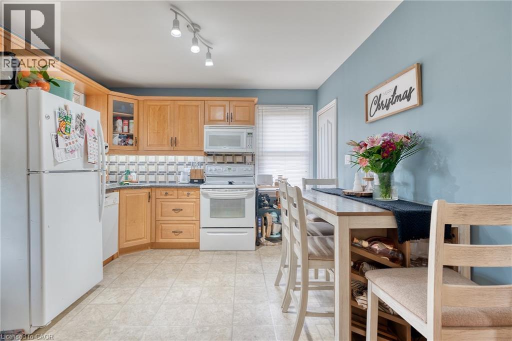 Kitchen featuring decorative backsplash, light brown cabinetry, white appliances, and light tile patterned floors - 99 East 36Th Street, Hamilton, ON - Indoor Photo Showing Other Room