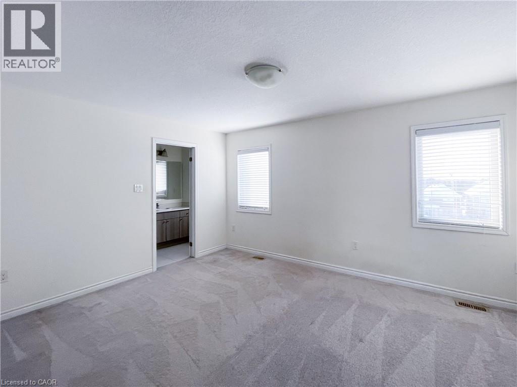Unfurnished bedroom with light colored carpet, a textured ceiling, and connected bathroom - 116 Watermill Street, Kitchener, ON - Indoor Photo Showing Other Room
