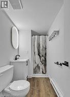 Full bathroom with a marble finish shower, vanity, a baseboard radiator, and wood finished floors -