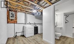 Laundry area with wood finished floors, electric panel, and washing machine and dryer -